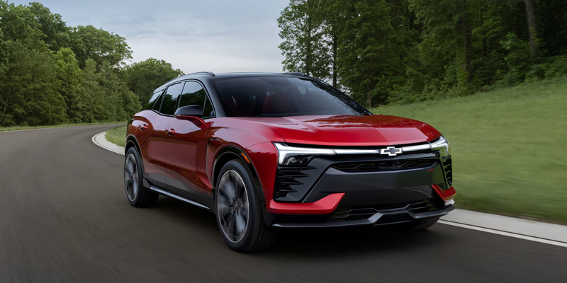 A red Chevrolet Blazer EV driving along a curved road.